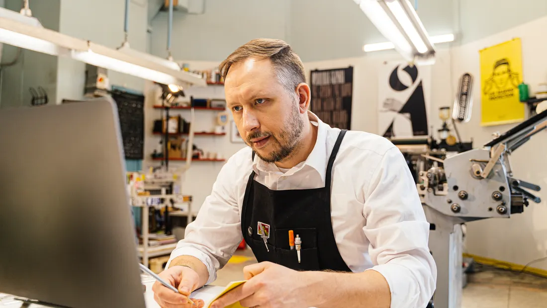 An owner of a print shop working at his computer on the shop floor