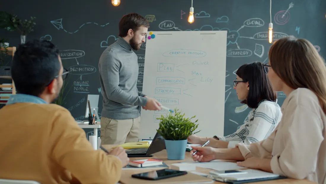 A team listening as a leader walks through a strategy at a whiteboard